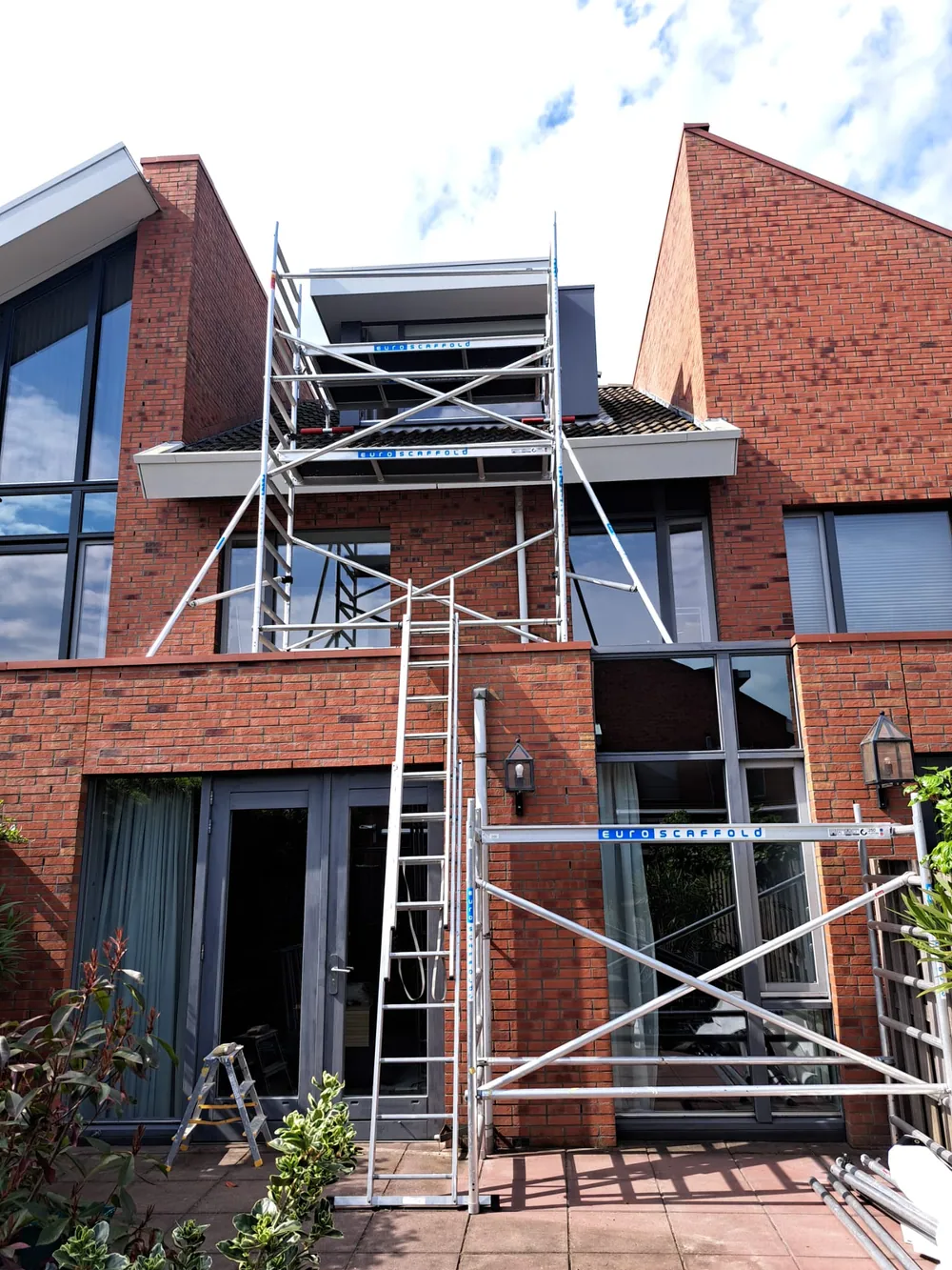 Buitenschilderwerk aan gevelkozijnen met steiger